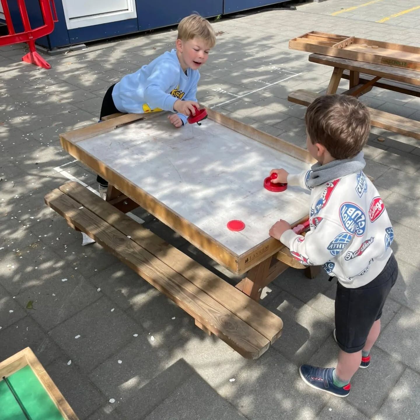 Kinderen spelen tafelhockey op de speelplaats