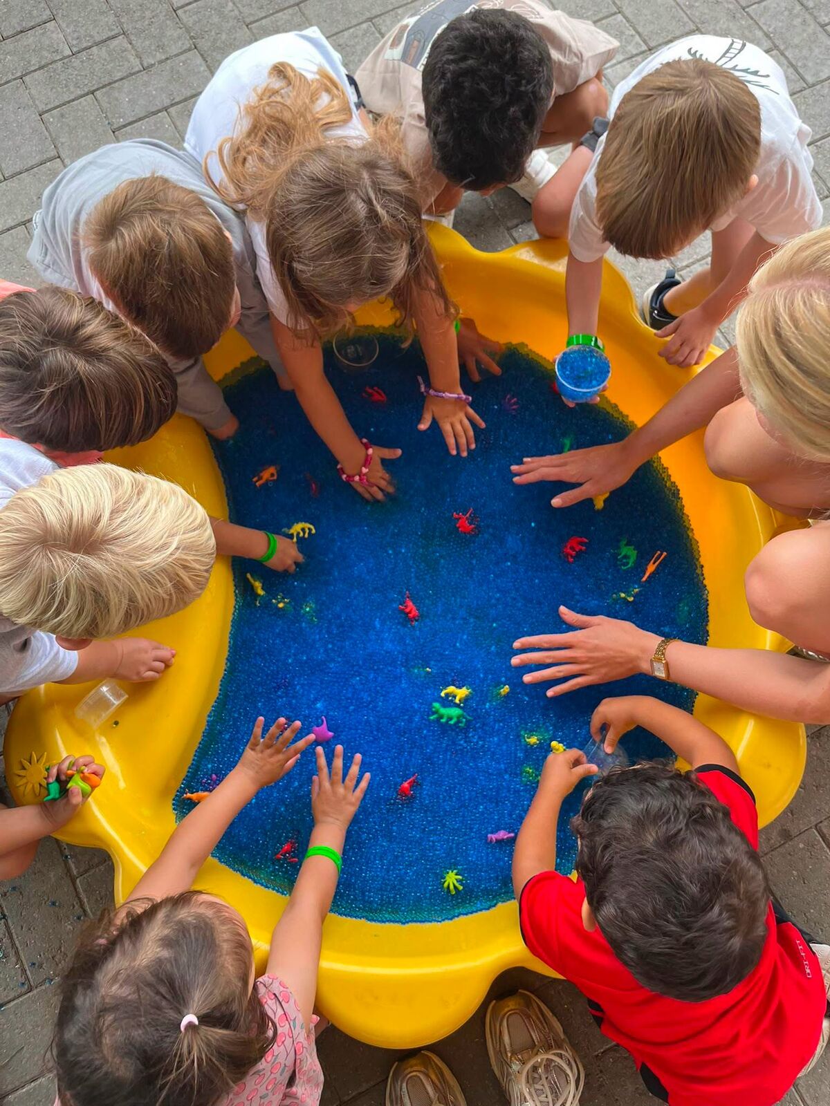 Kleuters ontdekken speeldiertjes in een bak met blauwe gelparels