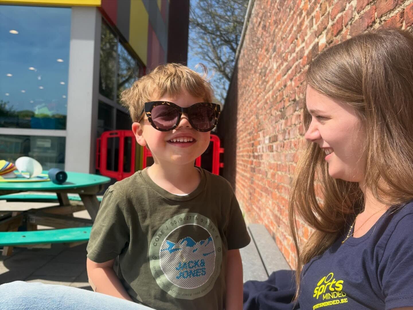 Een lachende jongen met zonnebril op kamp