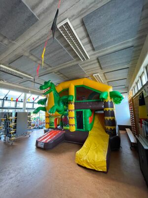 Springkasteel met dinosaurus en glijbaan in een sporthal